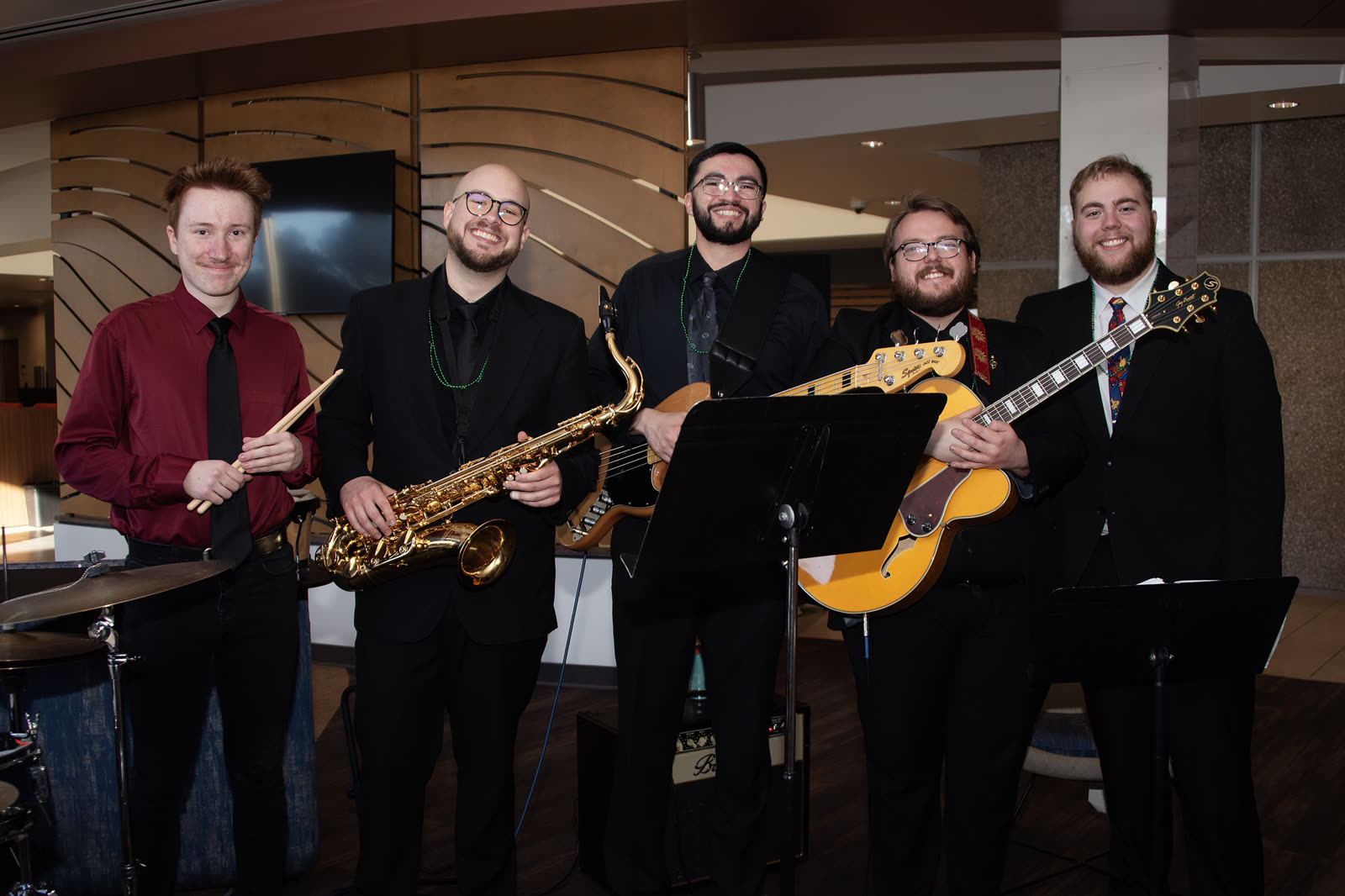 Band members posing with saxophone, guitar, and bass